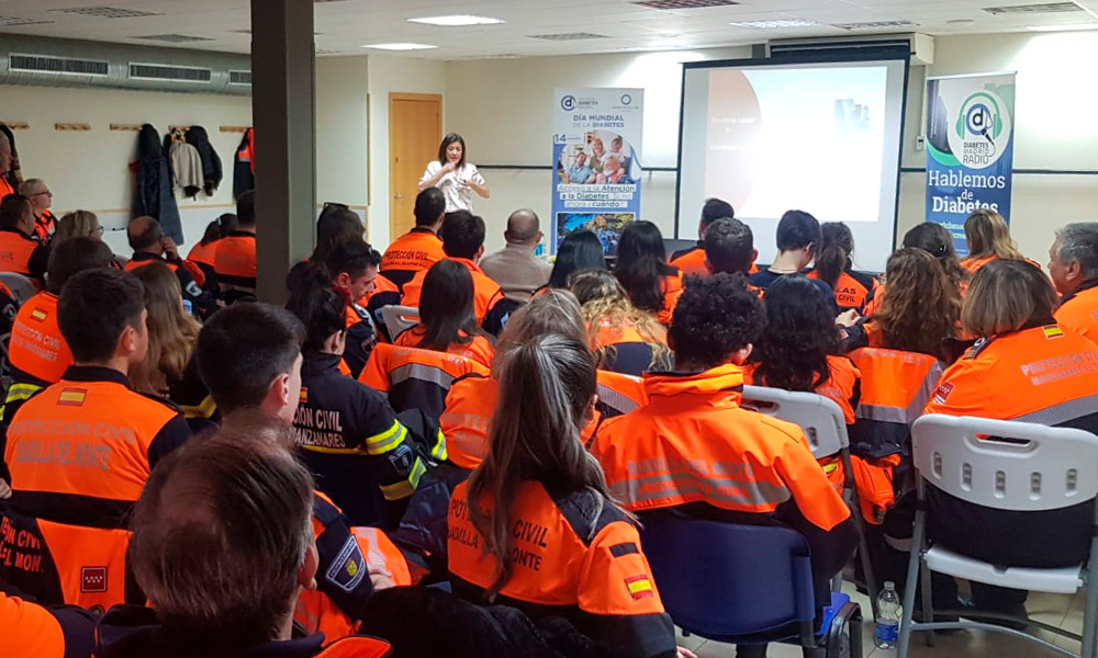 Una mujer da una presentación sobre Diabetes Madrid a trabajadores de Protección Civil, sentados frente a ella uniformados. 